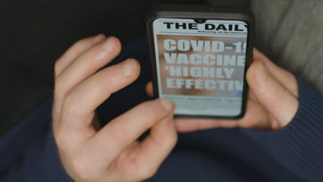 Nahaufnahme-Von-Händen,-Die-Einen-Nachrichtenartikel-Zu-Covid-Impfstoffen-Auf-Dem-Telefon-Scrollen