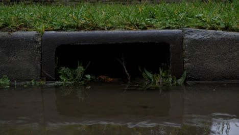 Close-Up-Shot-of-Roadside-Drain-During-Rain-Storm-