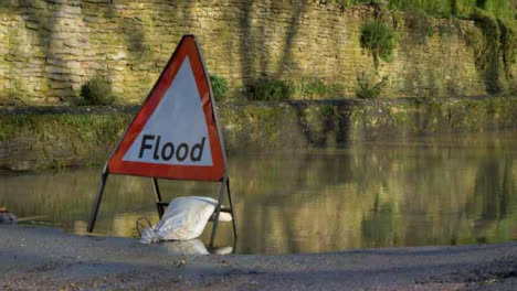 Close-Up-Shot-of-Flood-Road-Sign-In-Front-of-Flooded-Road