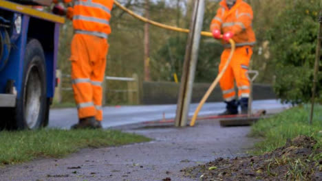 Disparo-Desenfocado-De-Trabajadores-De-Drenaje-Enrollando-La-Manguera-Del-Desagüe-En-La-Aldea-Inundada