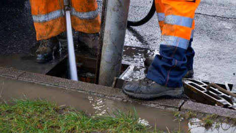 High-Angle-Shot-of-Drainage-Workers-Feet-as-They-Attempt-to-Clear-Out-Drain