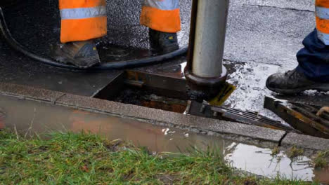 High-Angle-Shot-of-Drainage-Workers-as-They-Remove-Discarded-Car-Plate-from-Suction-Pipe
