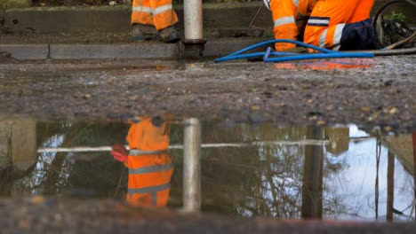 Low-Angle-Shot-of-Drainage-Worker-On-His-Knees-Attempting-to-Unblock-Drain