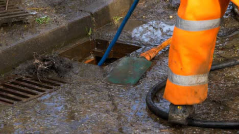 Handheld-Close-Up-Shot-of-Drainage-Workers-Attempting-to-Unblock-Drain-with-Hose