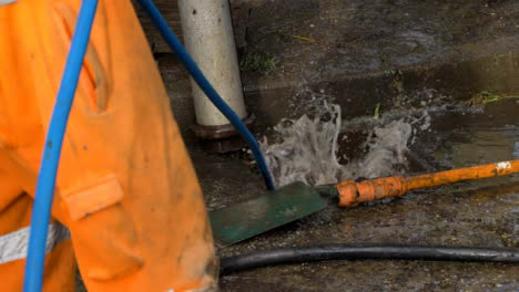 Handheld-Medium-Shot-of-Water-Bubbling-Up-as-Drainage-Workers-Attempt-to-Unblock-Drain