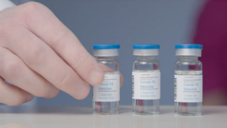 Schieben-Sie-Nahaufnahme-Von-Ärzten,-Die-Die-Durchstechflasche-Mit-Covid-Impfstoff-Aufheben