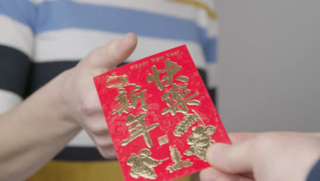 Nahaufnahme-Der-Hand,-Die-Der-Person-Einen-Roten-Umschlag-Des-Chinesischen-Neujahrs-Gibt