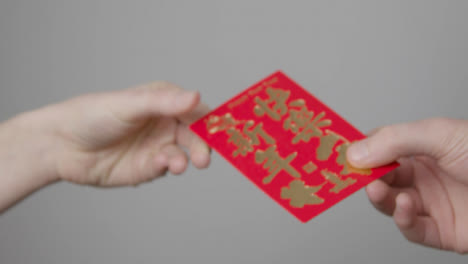 Nahaufnahme-Einer-Hand,-Die-Am-Chinesischen-Neujahr-Einen-Roten-Umschlag-Von-Einer-Anderen-Nimmt