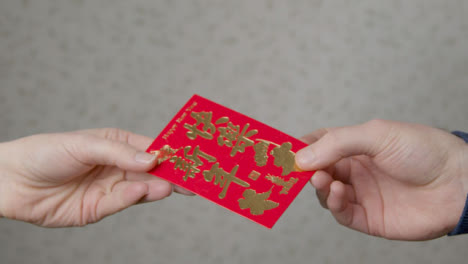 Close-Up-Shot-of-One-Hand-Taking-a-Red-Pocket-from-Another-On-Chinese-New-Year