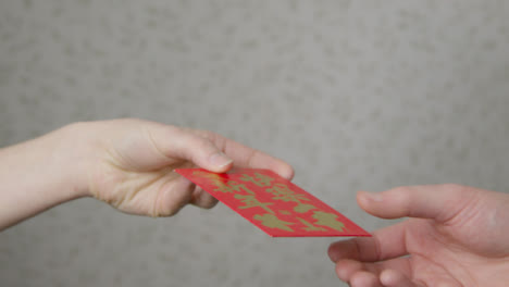 Nahaufnahme-Einer-Hand,-Die-Am-Chinesischen-Neujahr-Einen-Roten-Umschlag-Von-Einer-Anderen-Nimmt?