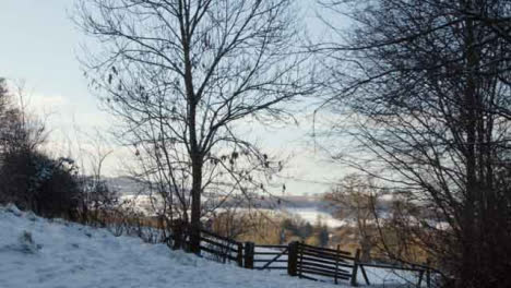 Tracking-Shot-Approaching-Fence-and-Gate-In-Snow-Covered-Countryside