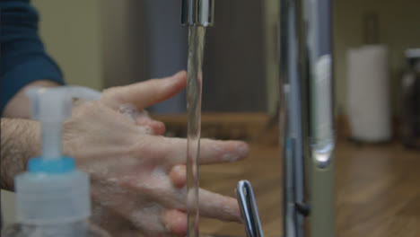 Close-Up-Shot-of-Male-Hands-Washing-Hands-Running-Under-Tap-with-Soap