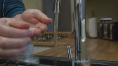 Plano-Medio-De-Manos-Masculinas-Girando-El-Grifo-De-La-Cocina-Y-Lavando-Con-Agua-Corriente