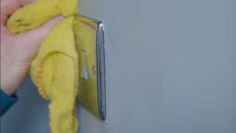 Close-Up-Shot-of-Male-Hand-Cleaning-Light-Switch-On-Wall