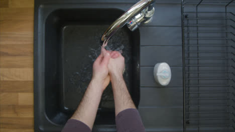 Top-Down-Aufnahme-Männlicher-Hände,-Die-Den-Wasserhahn-Aufdrehen-Und-Mit-Seife-Waschen