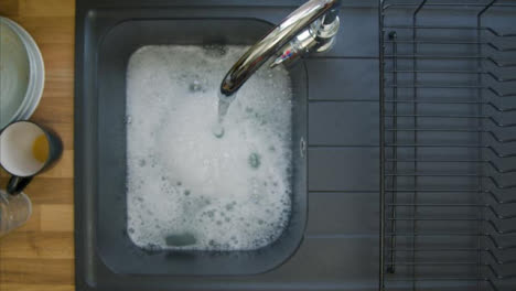Top-Down-Aufnahme-Einer-Männlichen-Hand,-Die-Seifenwasser-Im-Waschbecken-Mischt