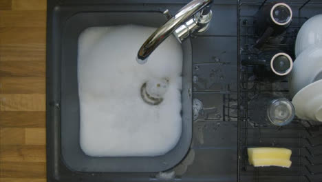 Top-Down-Shot-of-Soapy-Water-Running-Down-a-Sink-Plug-Hole-Leaving-Bubbles-Behind