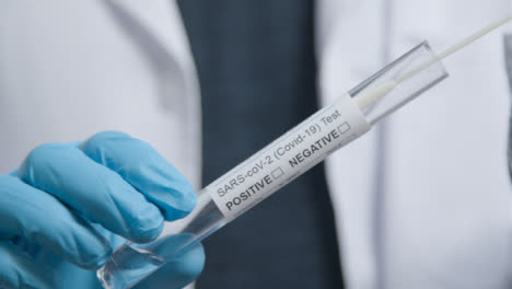 Close-Up-Shot-of-COVID-Test-Tube-as-Medical-Professional-Places-Swab-In-It