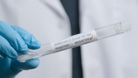 Close-Up-Shot-of-Doctor-Walking-Towards-Camera-Holding-Negative-COVID-Test-Tube-In-Hand