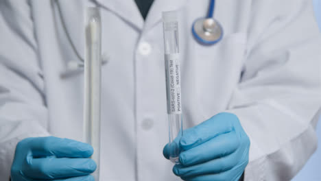 Close-Up-Shot-of-Medical-Professionals-Hands-Holding-COVID-Test-Tube-and-Swab-