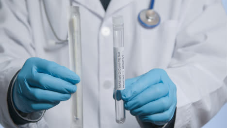 Close-Up-Shot-of-Doctor-Walking-Towards-Camera-Holding-COVID-Test-Tube-and-Swab-