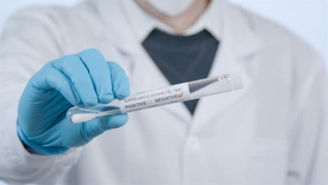 Close-Up-Shot-of-Doctor-Walking-Towards-Camera-Holding-a-Negative-COVID-Test-Tube-In-Hand