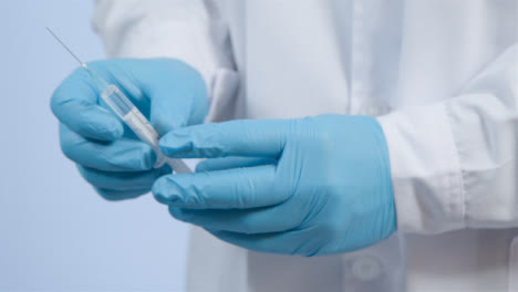 Close-Up-Shot-of-médico-Professionals-Hand-Holding-COVID-Vaccine-Syringe-and-Injecting-Off-Screen-Patient