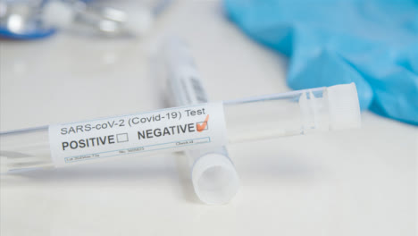 Sliding-Close-Up-of-COVID-Negative-Test-Tube-and-Swab-On-a-Table-Surface