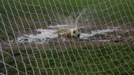 Mittlerer-Schuss-Des-Fußballs,-Der-In-Der-Pfütze-Im-Tormund-Landet