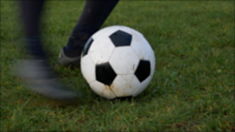 Defocused-Shot-of-Players-Boot-Kick-Stationary-Soccer-Ball-