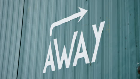 Handheld-Close-Up-Shot-of-Away-Soccer-Dressing-Room-Sign-On-Metal-Cabin-