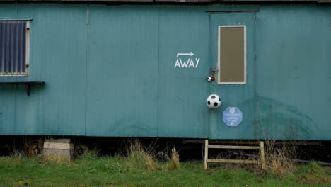 Wide-Shot-of-Soccer-Ball-Bouncing-Off-of-Metal-Cabin-Away-Dressing-Room