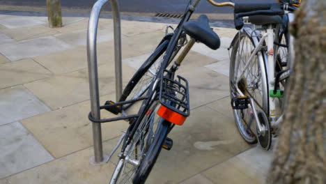 Tiro-De-Seguimiento-Pasado-árbol-Acercándose-Bicicletas-Bloqueadas-A-La-Baranda