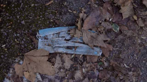 Handheld-Shot-of-Discarded-Face-Mask-On-Pavement-