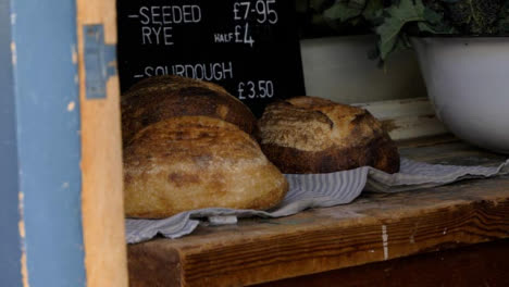 Handheld-Shot-of-Organic-Produce-Stores-Bread-Display-Behind-Door