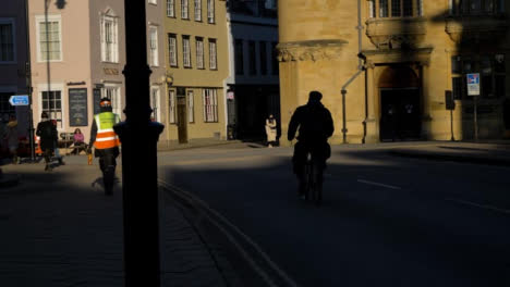 Handheld-Wide-Shot-of-Cyclist-Riding-Down-Street-
