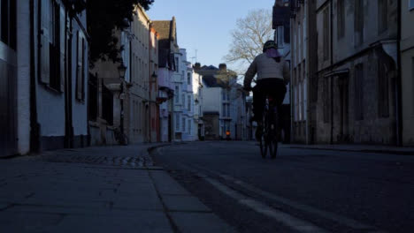 Low-Angle-Shot-of-Cyclist-Riding-Down-an-Old-Street