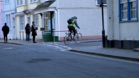 Handheld-Pull-Fokus-Aufnahme-Eines-Radfahrers,-Der-Um-Die-Straßenecke-Fährt