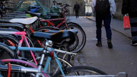Handheld-Shot-of-Bicycles-Locked-to-Racks-as-Pedestrians-Walk-Past