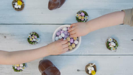Overhead-Shot-of-Young-Children's-Hands-Taking-Chocolate-Eggs-from-Bowl