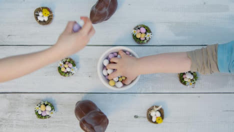 Overhead-Shot-of-Young-Children's-Hands-Taking-Handfuls-of-Chocolate-Eggs-from-Bowl