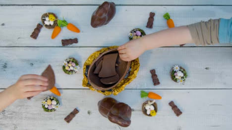 Overhead-Shot-of-Young-Children's-Hands-Taking-Pieces-of-Chocolate-Egg-from-Table