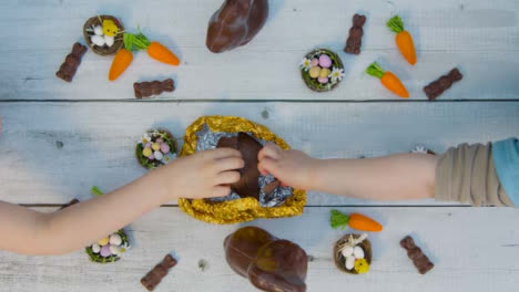 Overhead-Shot-of-Adult-and-Children's-Hands-Taking-Last-Pieces-of-Chocolate-Egg-from-Table