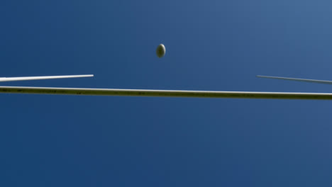 Low-Angle-Shot-Looking-Up-at-Rugby-Posts-as-a-Rugby-Ball-Flies-Over