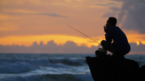 Handheld-Long-Shot-of-Fisherman-Silhouetted-Against-Sunset