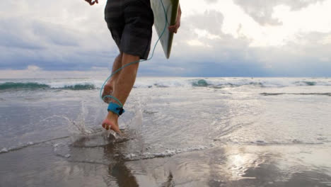 Handheld-Tracking-Shot-Following-Surfer-Running-Into-Sea
