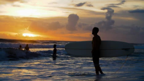 Handheld-Medium-Shot-of-Surfers-at-Echo-Beach-Shore-Silhouetted-Against-Sunset