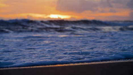 Handheld-Close-Up-Shot-of-Waves-On-Echo-Beach-Shore-at-Sunset