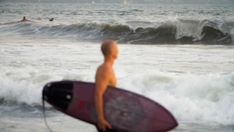 Defocused-Handheld-Long-Shot-of-Surfer-Walking-Along-Shore