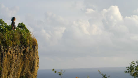 Wide-Shot-of-Person-Standing-On-Cliff-Edge-Looking-Out-at-Ocean